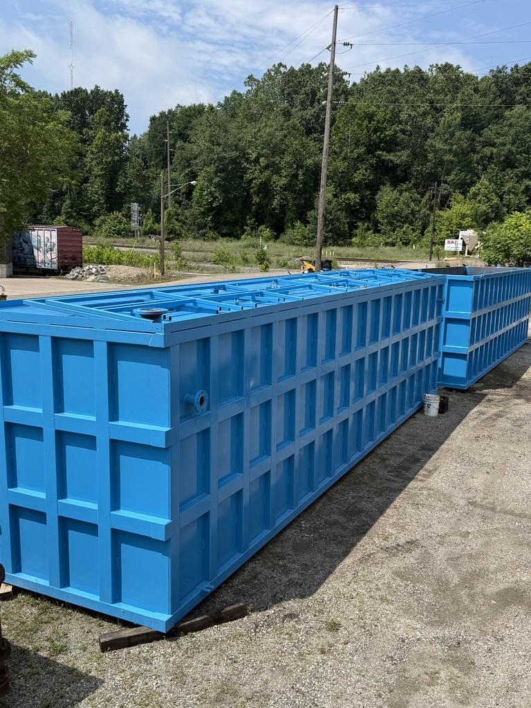 Two long open-top blue EnviroBox tanks side by side in the yard